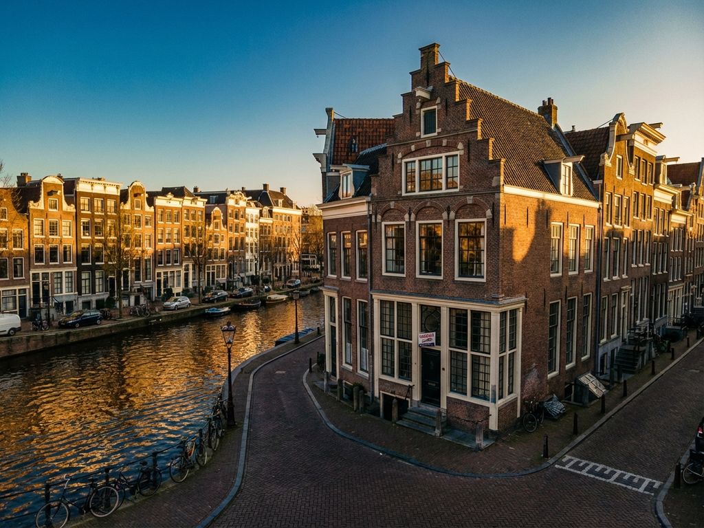Luchtfoto van Amsterdamse grachtenring met historisch herenhuis met VERKOCHT bord tijdens gouden uur