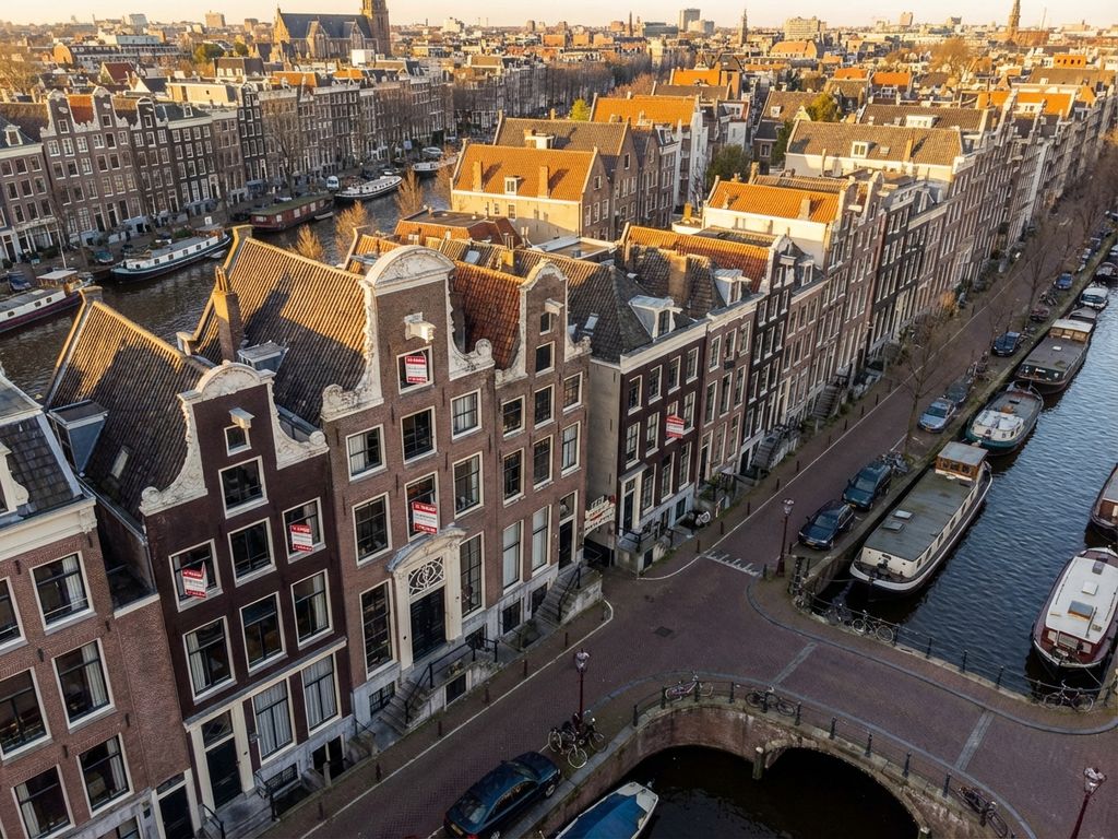 Luchtfoto van Amsterdamse grachtenpanden met 'Te Koop' borden tijdens gouden uur, historische architectuur en fietsen